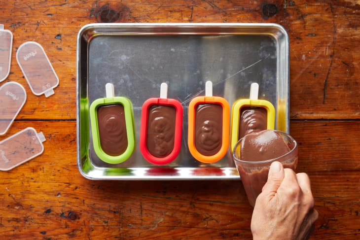 Someone pouring fudge into popsicle molds.