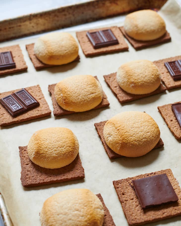S'mores are laid out on a sheet pan; graham crackers, chocolate, and toasted marshmallows.