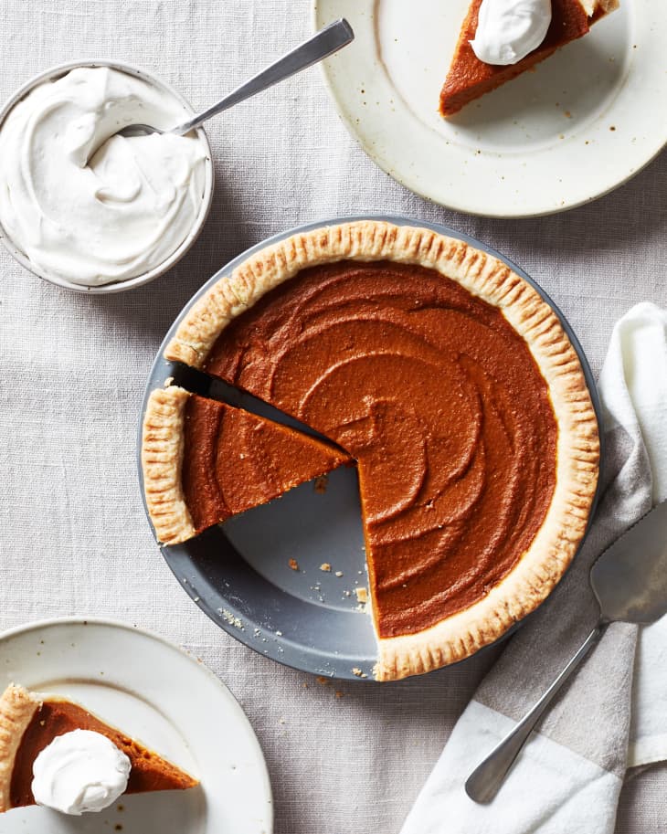 The vegan pumpkin pie is cut into. Two slices sit on plates and are topped with coconut yogurt.