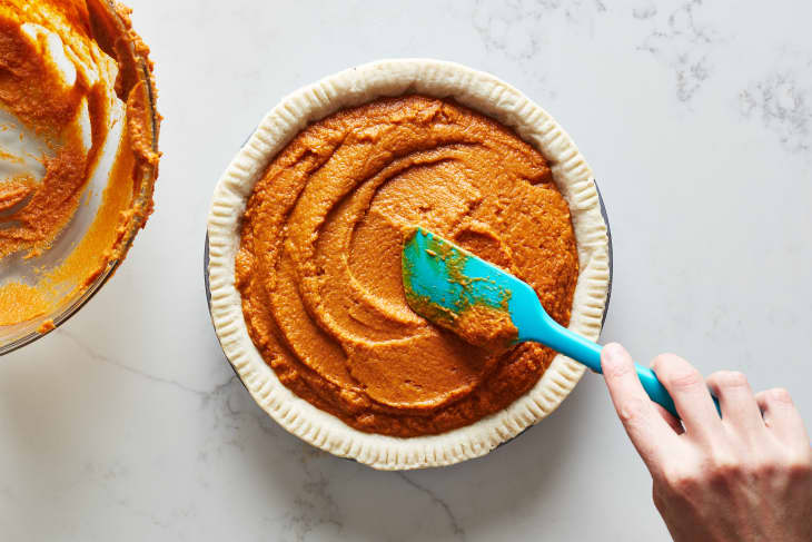 With a spatula, the pumpkin pie filling is spread with in the pie shell.