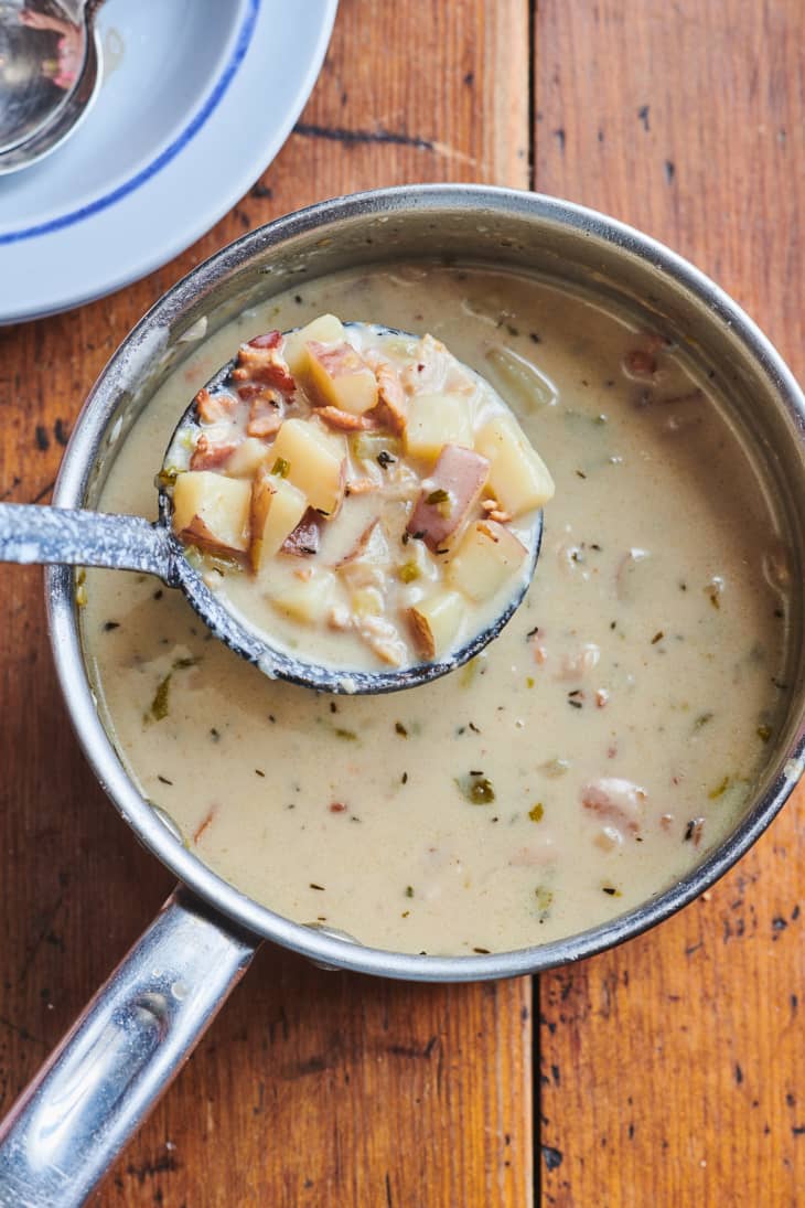 New England clam chowder lifted out of pot with ladle.