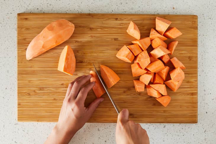 Yams being cubed on cutting board.