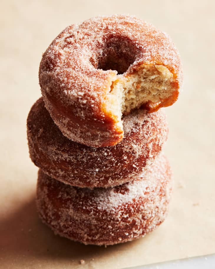Apple cider donuts stacked up with top donut bitten.