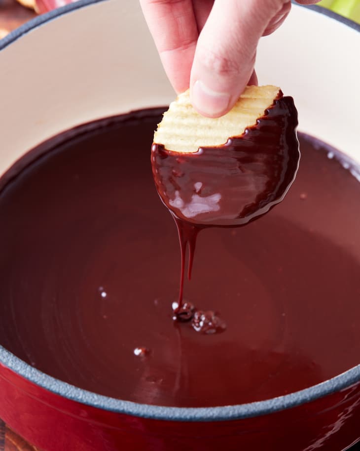 someone is dipping a chip into the fondue pot of chocolate