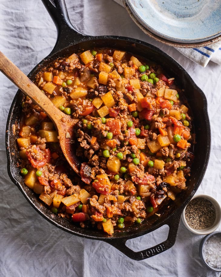 picadillo is in a cast iron pot with a spoon
