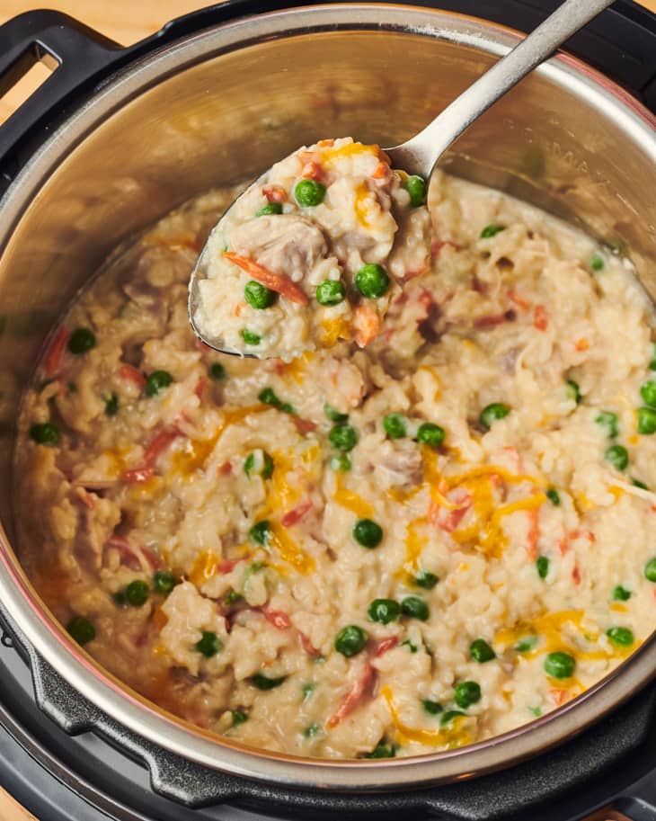 someone is pulling chicken and rice out of instant pot with a met al spoon