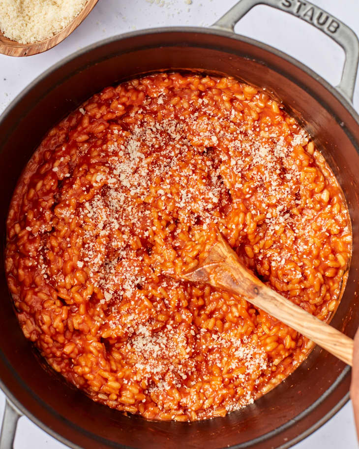tomato risotto cooking in a pot with wooden spoon