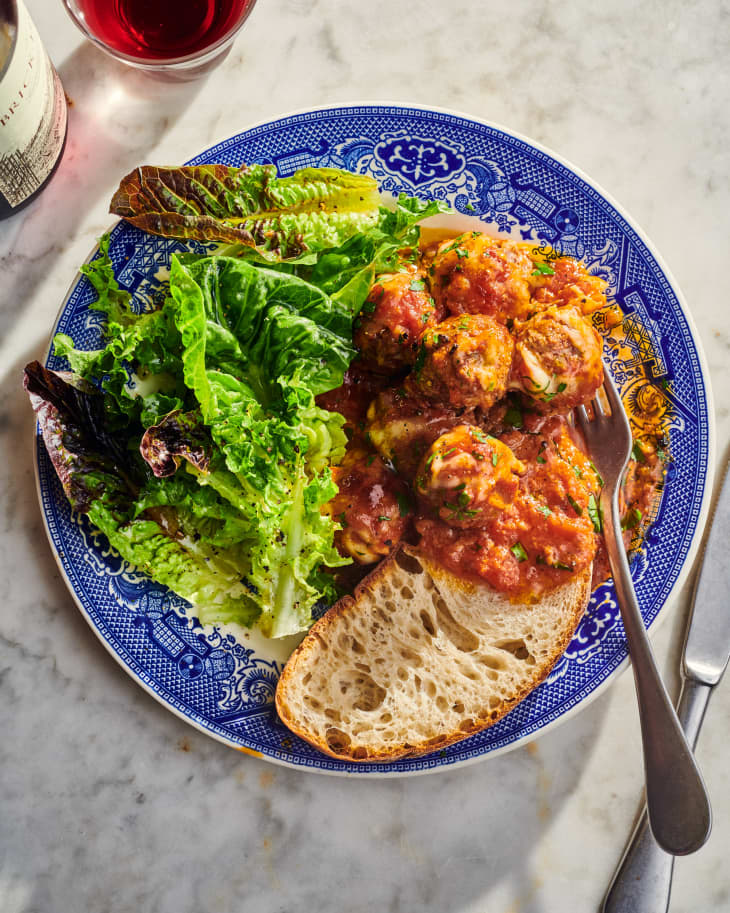 meatball caserole on a plate with salad and bread