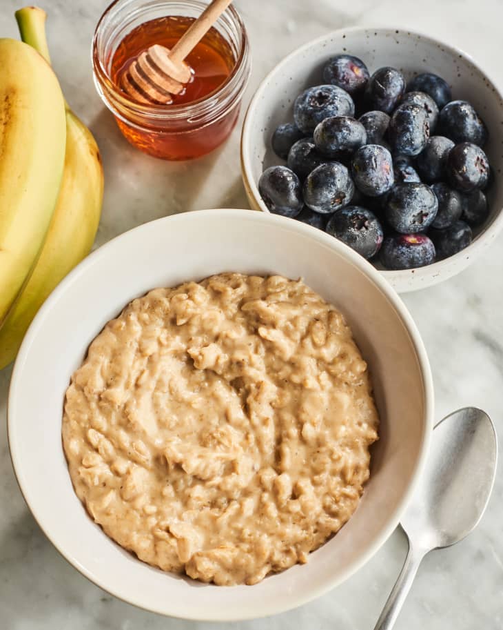 peanut butter oatmeal in a bowl with fruit and honey near it