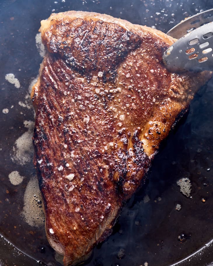 tight shot of tri tip steak searing in a pan