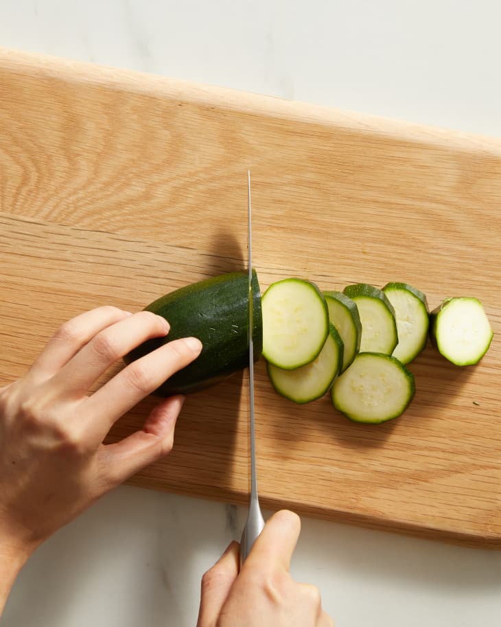 someone cutting zucchini with a knife