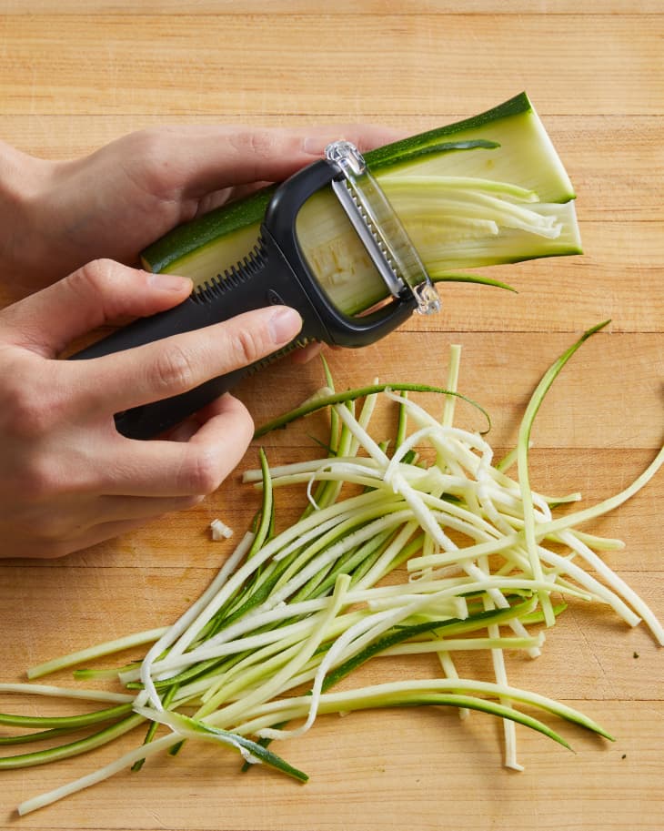 slicing zucchini with a vegetable peeler