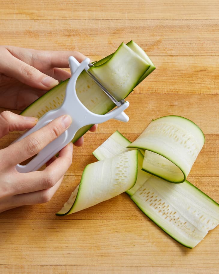 slicing zucchini with a vegetable peeler