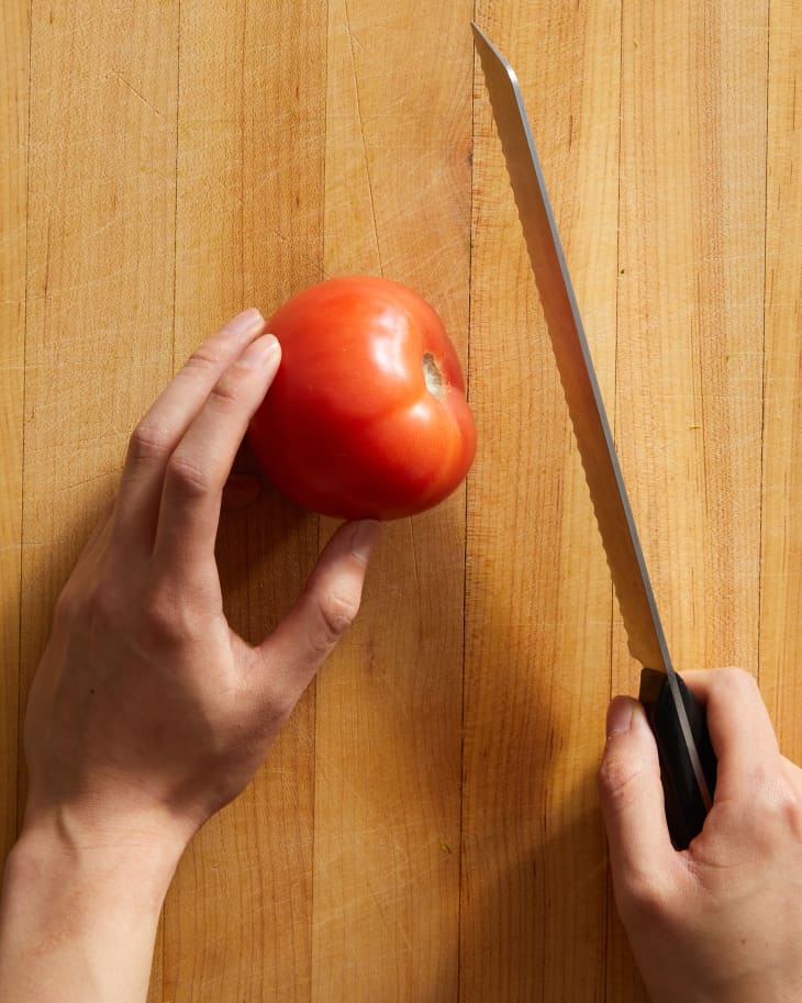 someone slicing a tomato in half