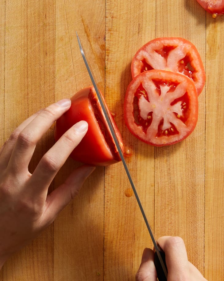someone slicing tomatoes into rounds