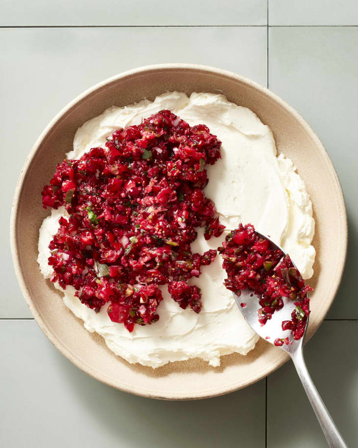 Cranberry topping being placed top of cream cheese spread.
