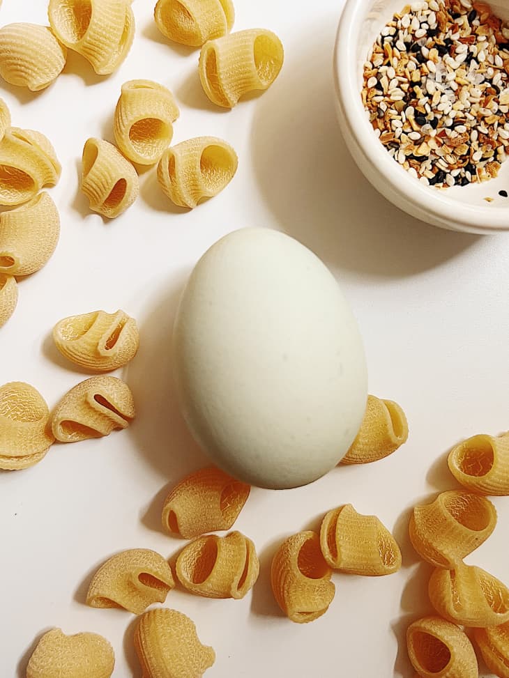 pasta, one egg, grains in a bowl on white surface