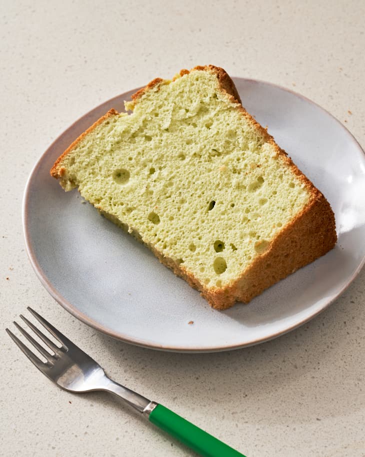 Photo of a slice of pandan cake on a plate with a fork next to it