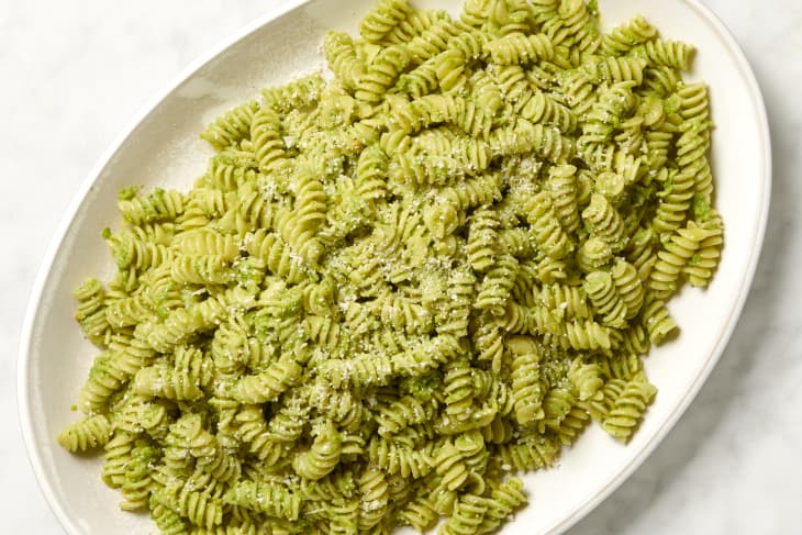 pasta with garlic scape pesto in a serving dish on a marble surface