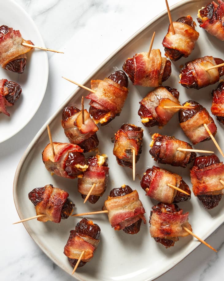 Overhead view of bacon wrapped dates on a beige platter with toothpicks in them.
