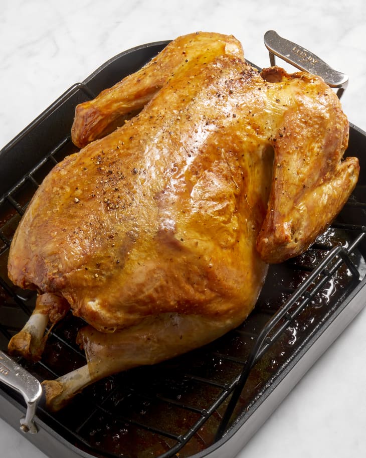 Angled view of a whole roasted turkey in a black pan.