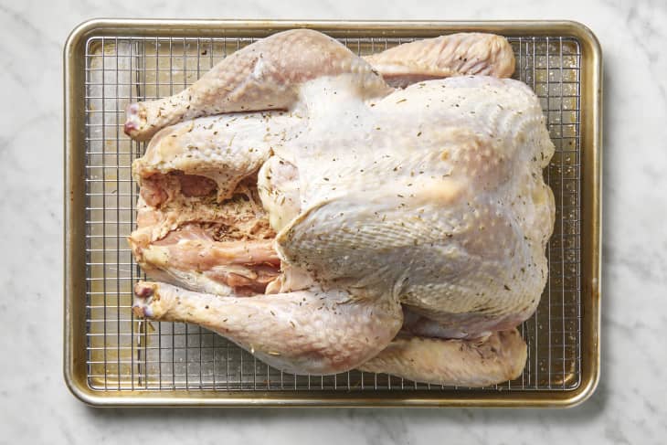 Overhead view of a raw, seasoned, turkey on a cooling rack.