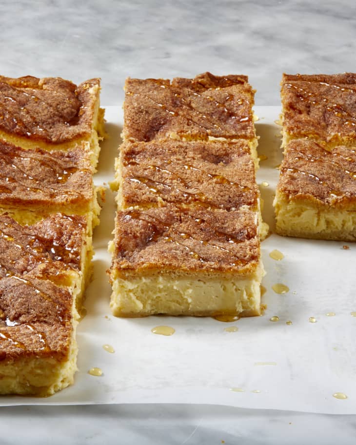 Angled view of cheesecake squares on a marble surface, drizzled with honey.
