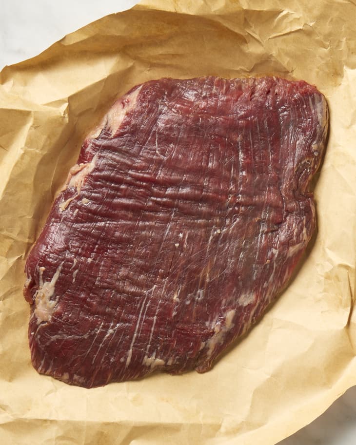 Overhead view of a cut of flank steak on brown butcher paper.