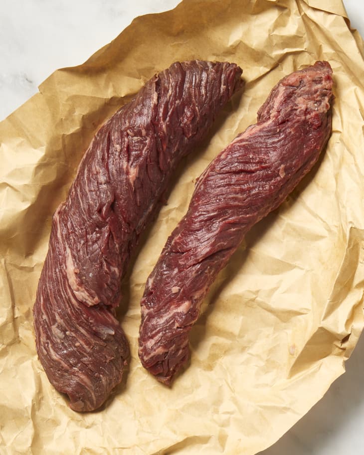 Overhead view of two cuts of hanger steak on brown butcher paper.
