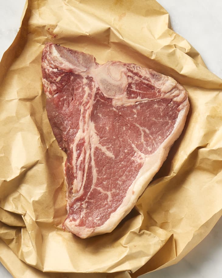 Overhead view of a t-bone steak on brown butcher paper.