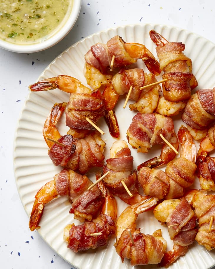 A platter of bacon wrapped shrimp with a dipping bowl of compound lemon butter.
