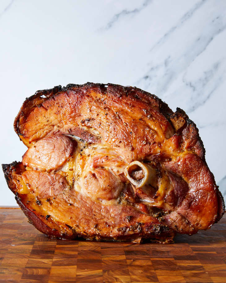 A baked ham on a wooden cutting board.