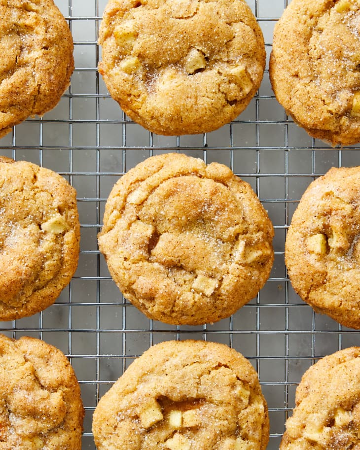 Caramel apple cookies cooling on a silver baking rack on a marble surface.