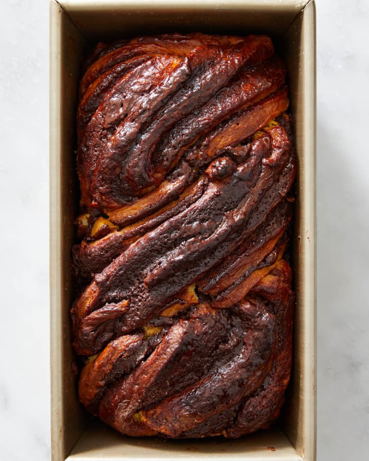 A whole chocolate babka in a loaf baking pan.