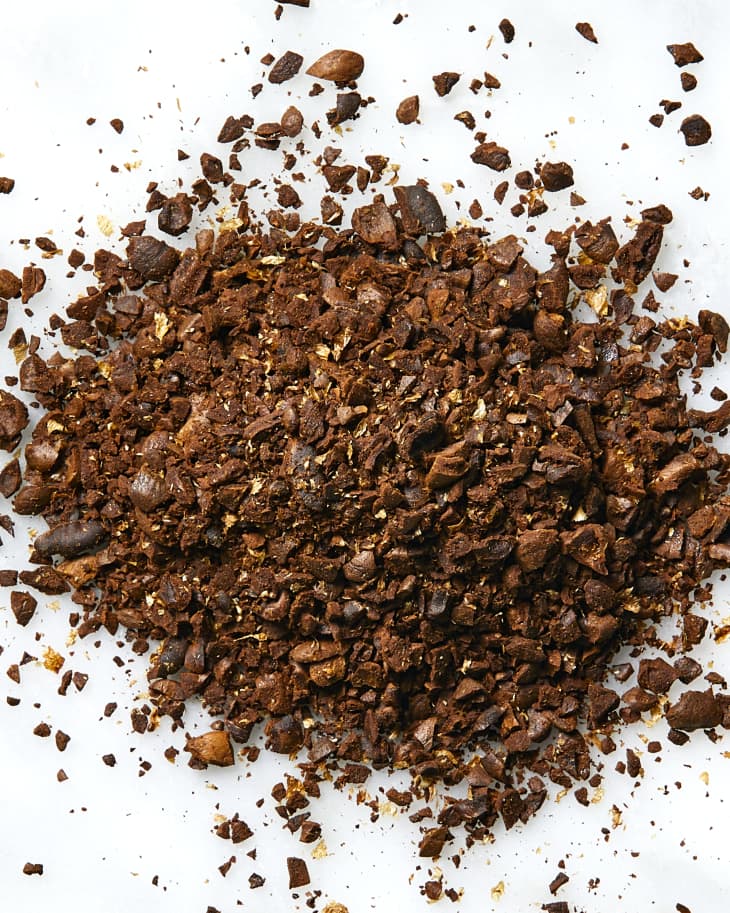Overhead view of coffee grounds in a small pile on a white surface.