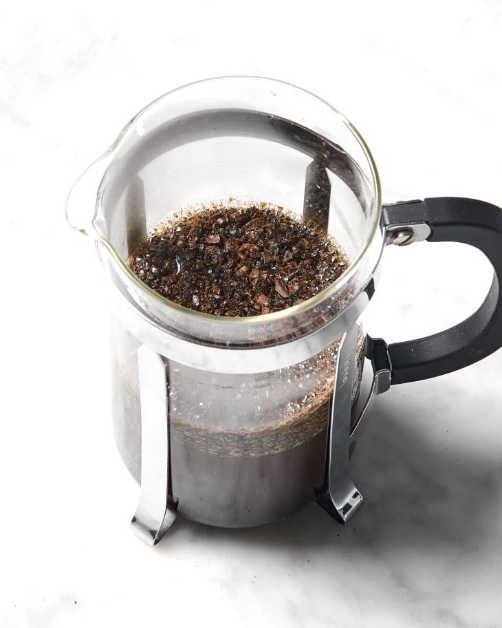 Angled overhead shot of coffee grounds at he top of the french press.