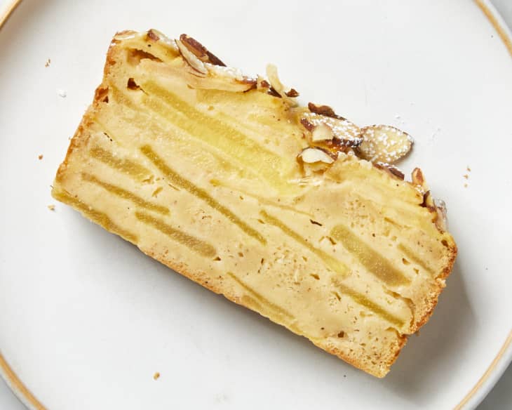 Overhead view of a slice of apple cake on a white plate with gold trim.