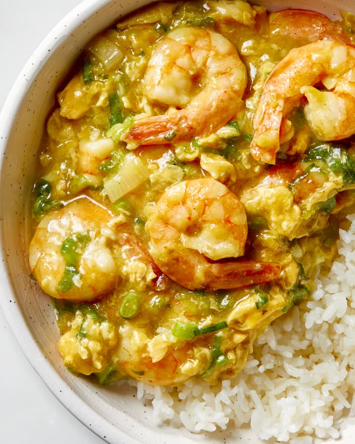 Close up shot of the shrimp with lobster sauce poured over a bed of rice, in a white and black speckled bowl.