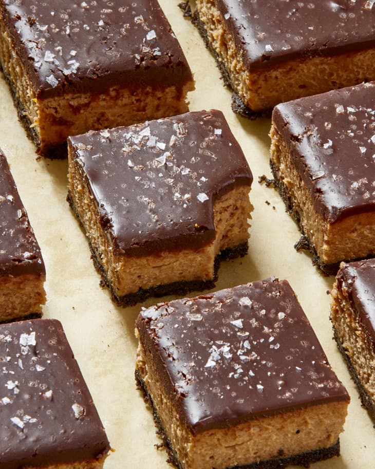 Angled view of rows of buckeye cheesecake bars with the middle on with a bite out of it.