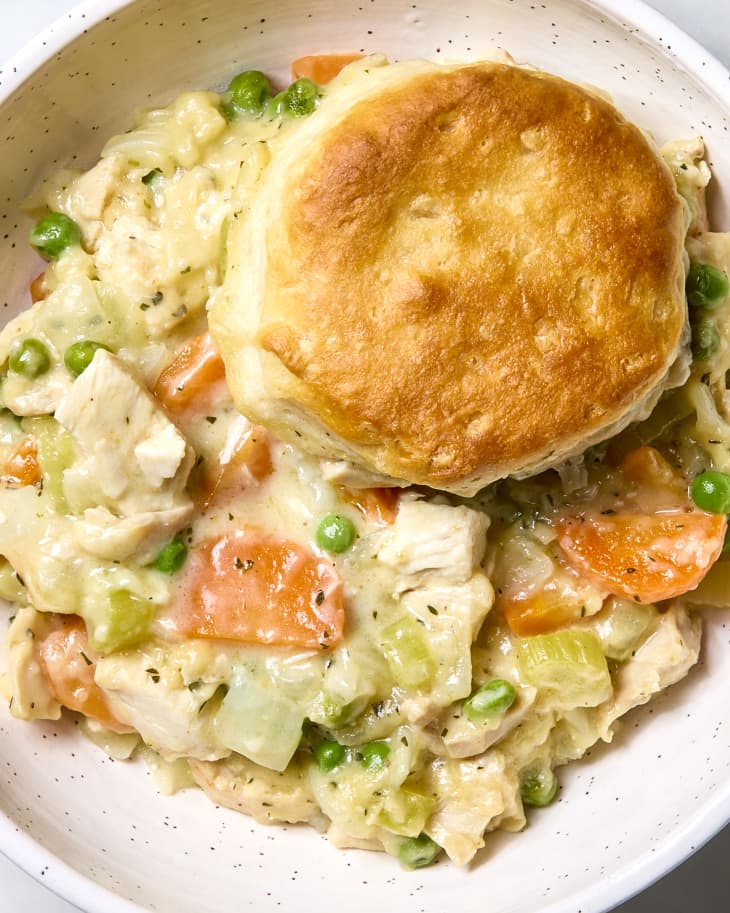Overhead shot of chicken pot pie casserole in a bowl, topped with a biscuit.