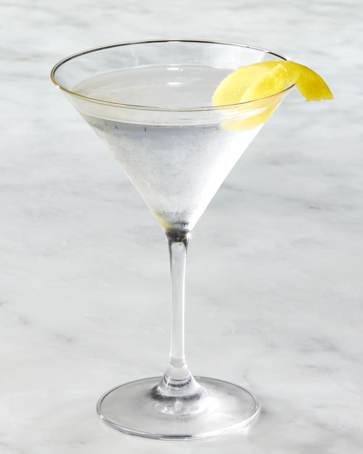 Head on shot of a classic martini with a lemon twist resting on the rim of the glass.