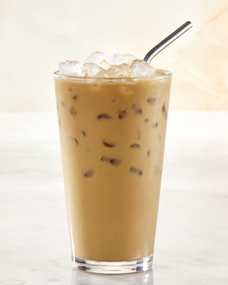 Head on shot of iced milk tea in a pint glass with a metal straw resting in it.