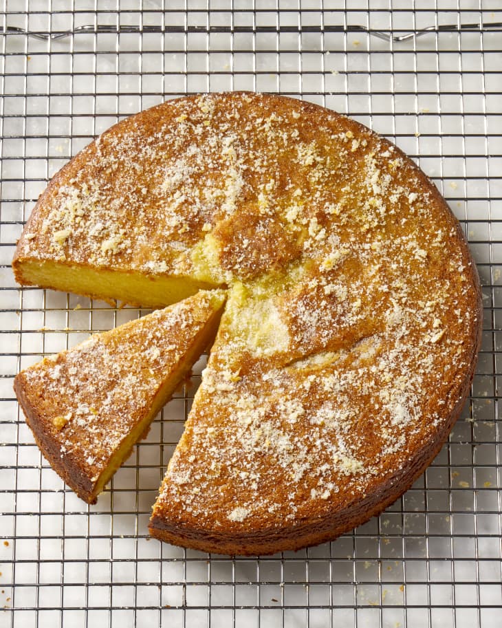 Overhead shot of olive oil cake on a cooling rack, with a slice cut out of it.