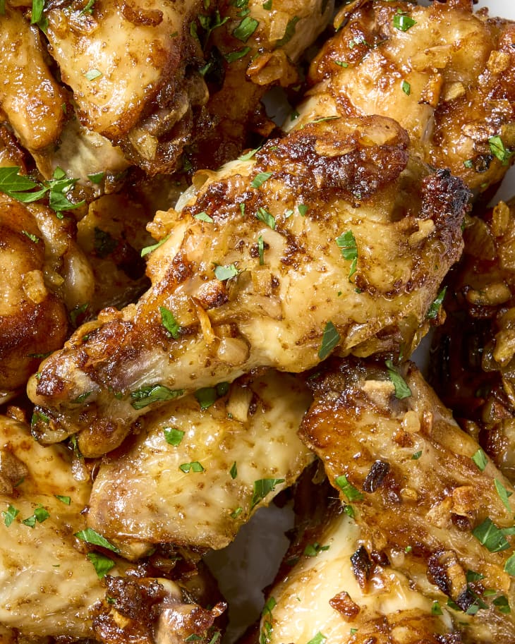 overhead shot of a large plate of french onion dip chicken wings, topped with herbs.