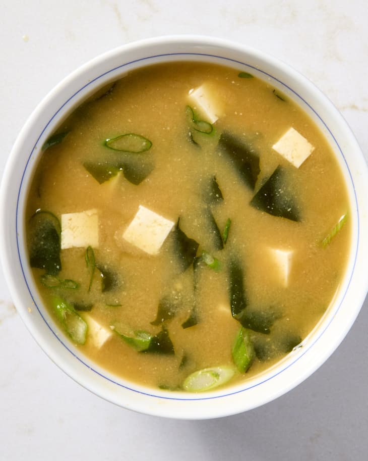 A bowl of miso soup on a marble background.