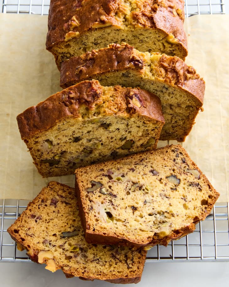 banana bread on brown parchment on wire rack with slices falling off