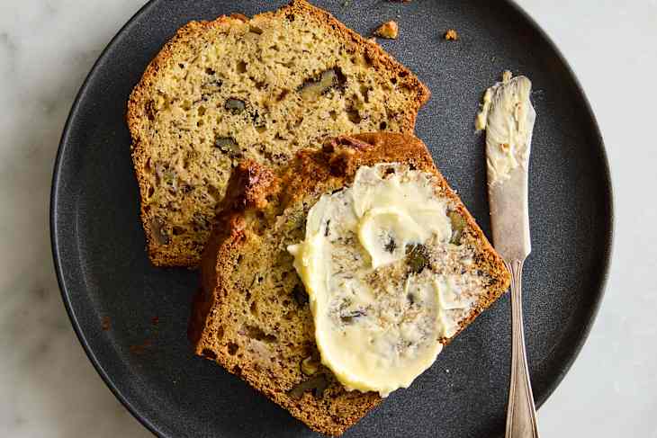 slices on dark plate with butter on banana bread