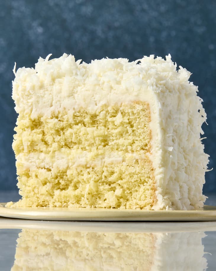 head on shot of a single slice of coconut cake on a small beige plate.