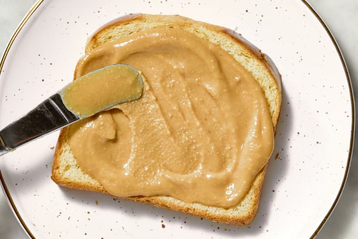 overhead shot of peanut butter spread on a piece of toasted bread.