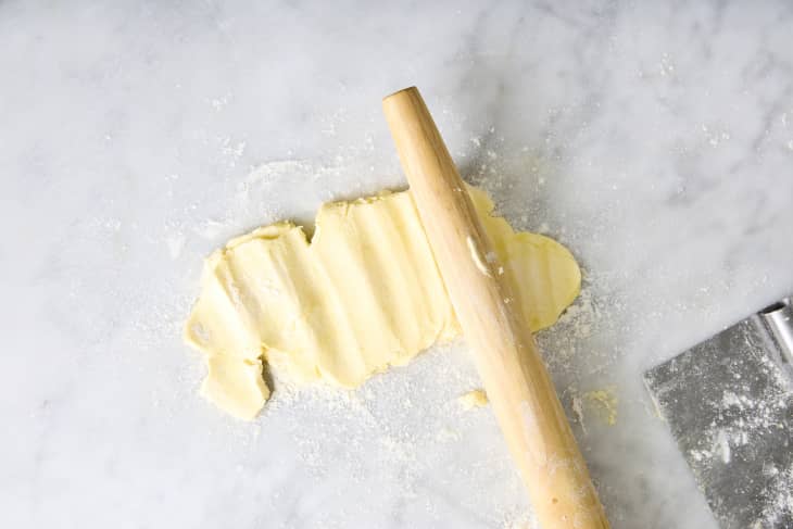 someone flattening butter with a rolling pin